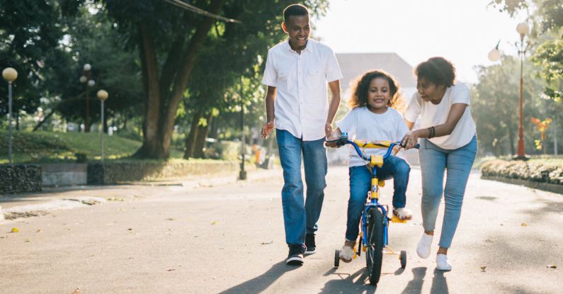 Families - Man Standing Beside His Wife Teaching Their Child How to Ride Bicycle